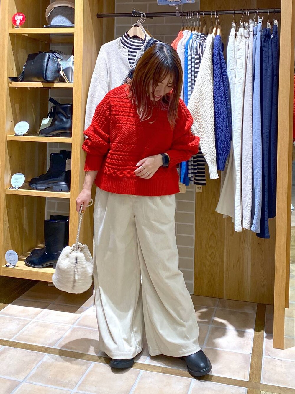 ブラック系のブーツ、ベージュ系のハンドバッグ、シルバー系のネックレスを着用したレディースの秋コーディネートの4枚目の写真