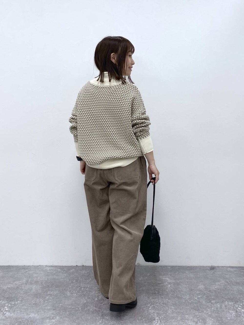 グレー系のその他パンツ、ブラック系のブーツ、ホワイト系のニット/セーターを着用したレディースの秋コーディネートの7枚目の写真