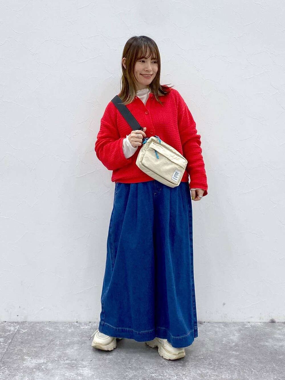 ベージュ系のショルダーバッグ、ブルー系のデニムパンツ、レッド系のカーディガン/ボレロを着用したレディースの春コーディネートの3枚目の写真