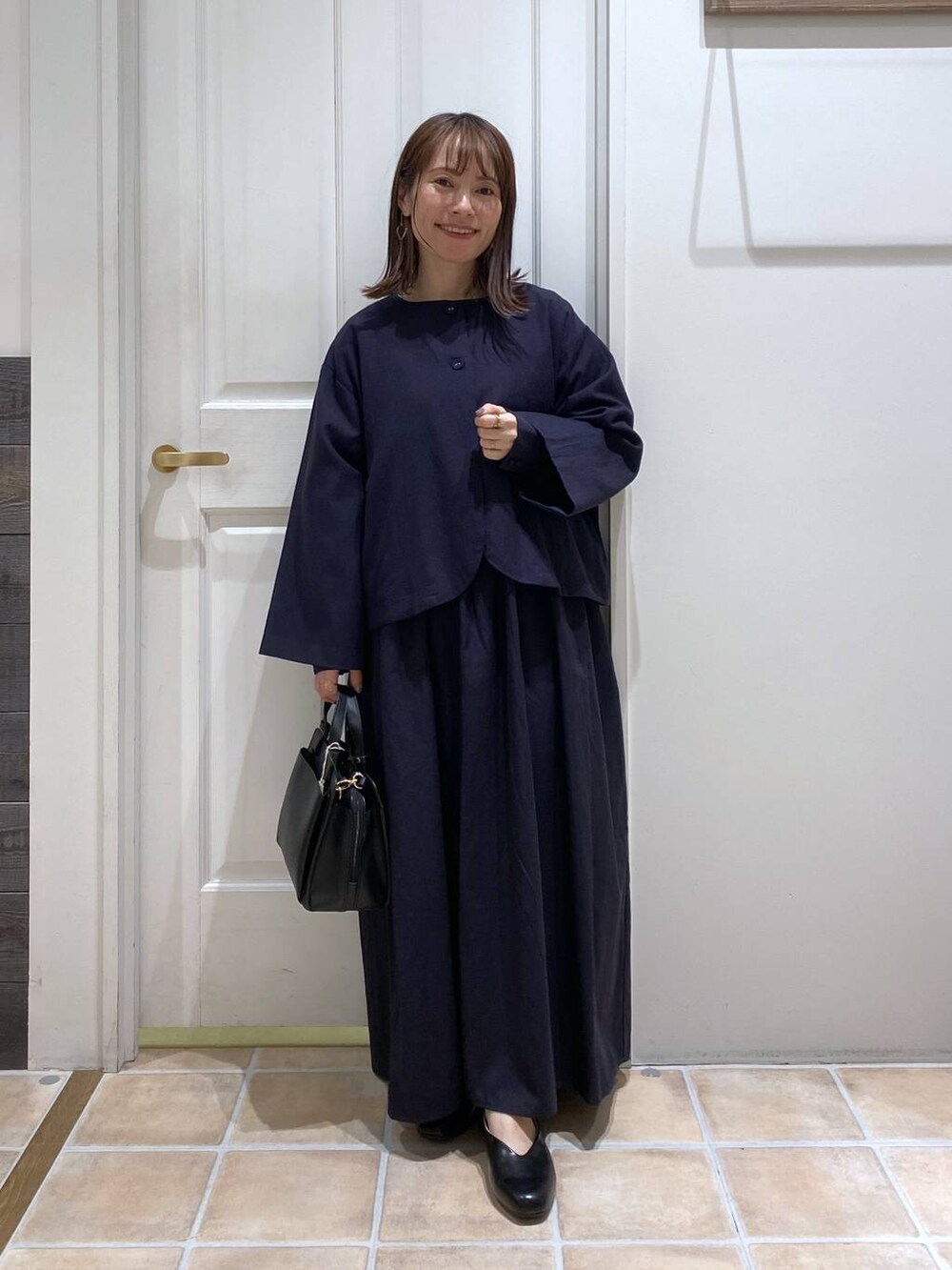 ブラック系のパンプス、ブルー系のセットアップ、その他のピアス（両耳用）を着用したレディースの冬コーディネートの2枚目の写真