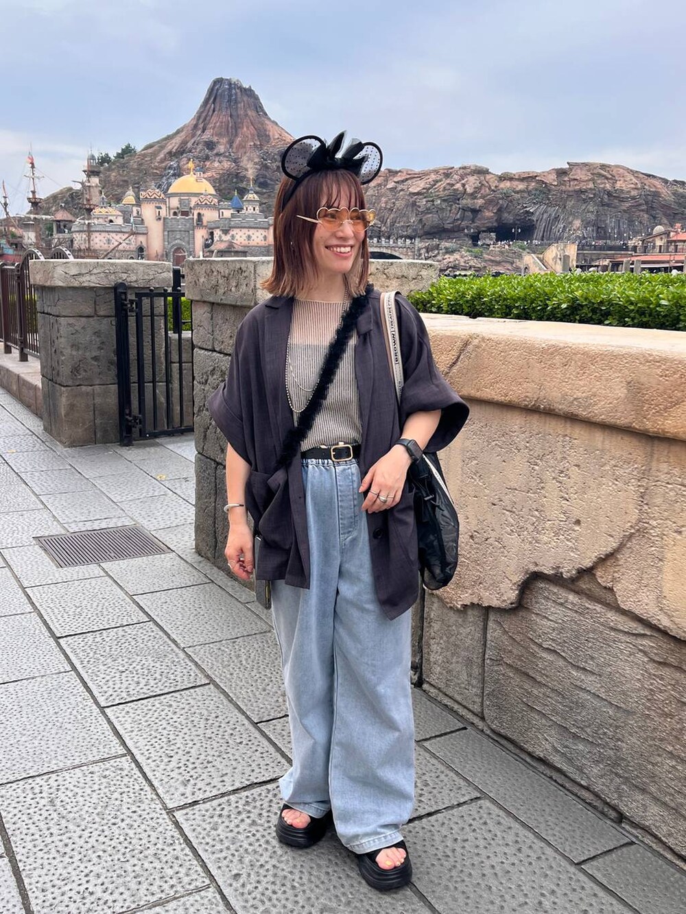 ブラック系のサンダル、ブルー系のデニムパンツ、グレー系のテーラードジャケットを着用したレディースの夏コーディネートの2枚目の写真