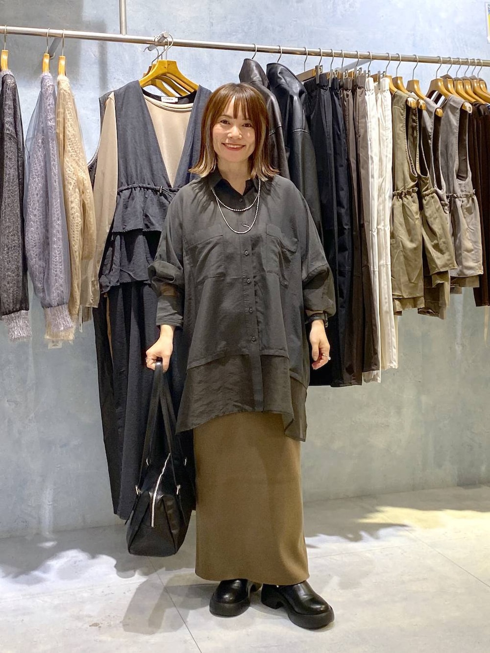 グレー系のシャツ/ブラウス、ブラック系のスカート、ブラック系のサンダルを着用したレディースの秋コーディネートの3枚目の写真