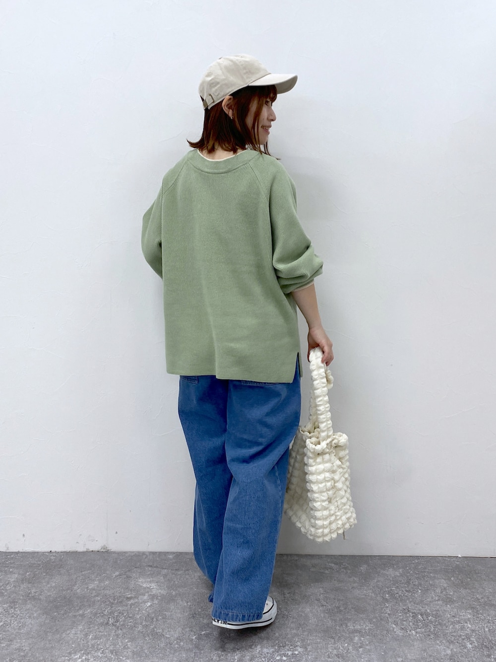 ブルー系のデニムパンツ、グリーン系のニット/セーター、ホワイト系のキャップを着用したレディースの冬コーディネートの4枚目の写真