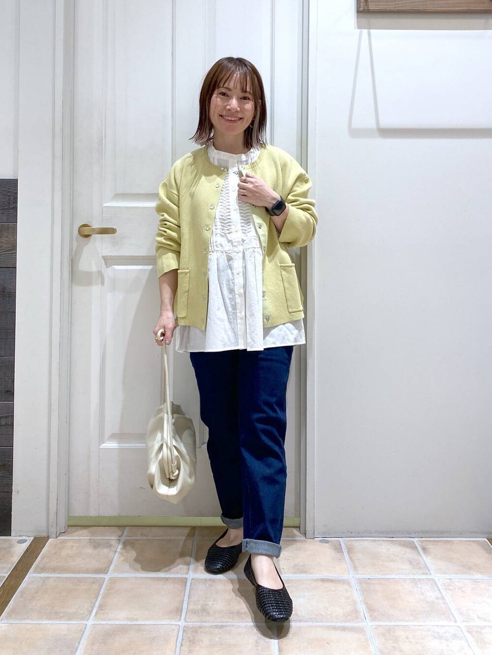 ホワイト系のショルダーバッグ、ブルー系のデニムパンツ、ホワイト系のビジネスシャツを着用したレディースの春コーディネートの2枚目の写真