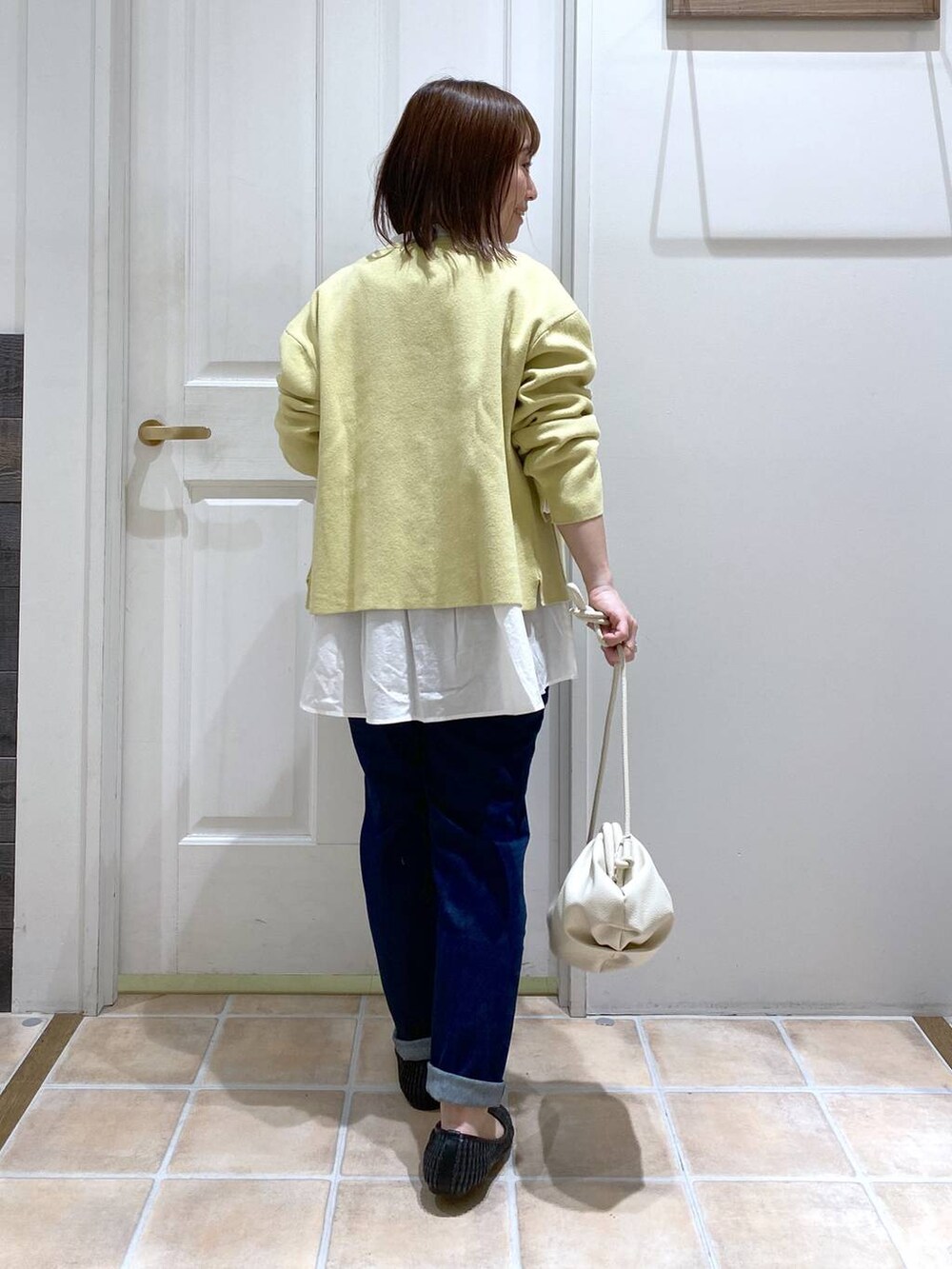 ホワイト系のショルダーバッグ、ブルー系のデニムパンツ、ホワイト系のビジネスシャツを着用したレディースの春コーディネートの6枚目の写真