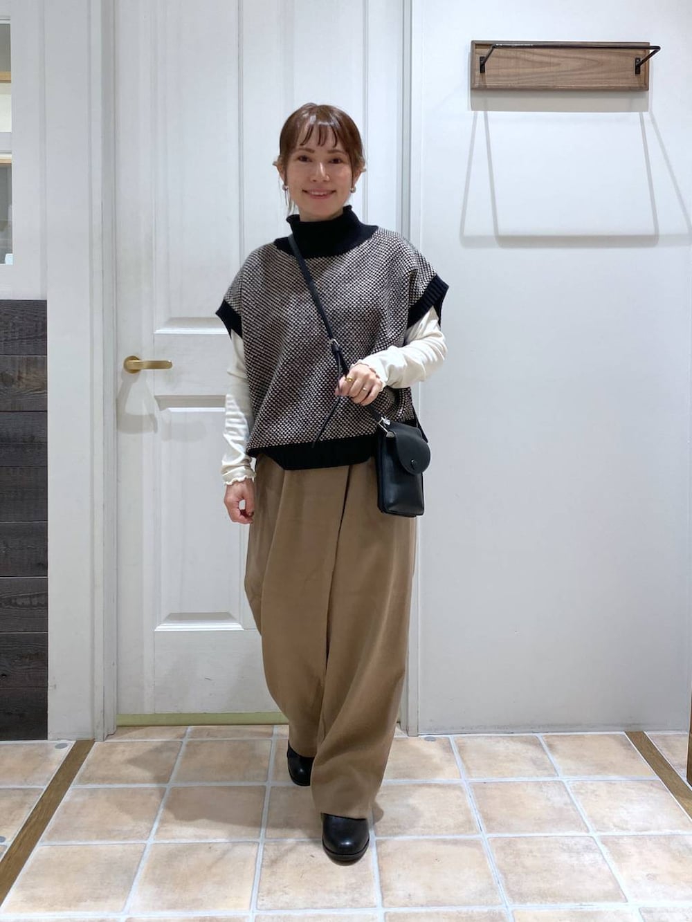 ホワイト系のTシャツ/カットソー、ブラック系のブーツ、ブラック系のベストを着用したレディースの冬コーディネートの2枚目の写真