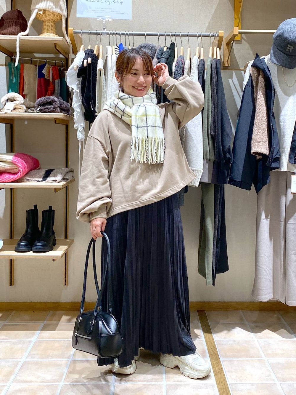 グレー系のスカート、ブラック系のトートバッグ、ベージュ系のTシャツ/カットソーを着用したレディースの冬コーディネートの3枚目の写真