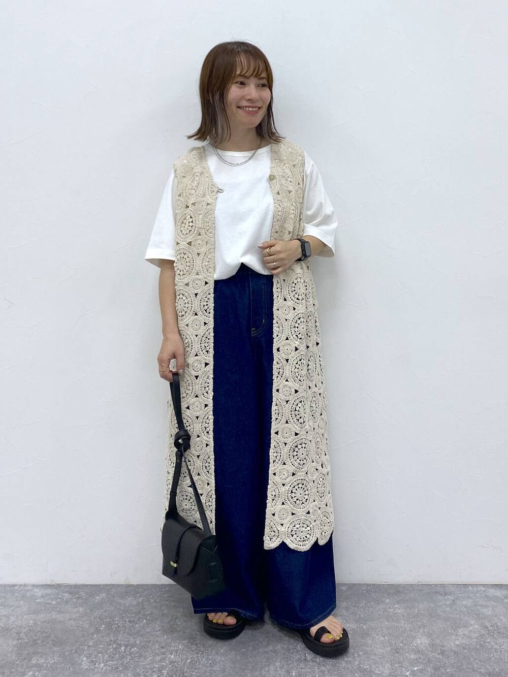 ブラック系のサンダル、ホワイト系のTシャツ/カットソー、ブラック系のショルダーバッグを着用したレディースの夏コーディネートの2枚目の写真