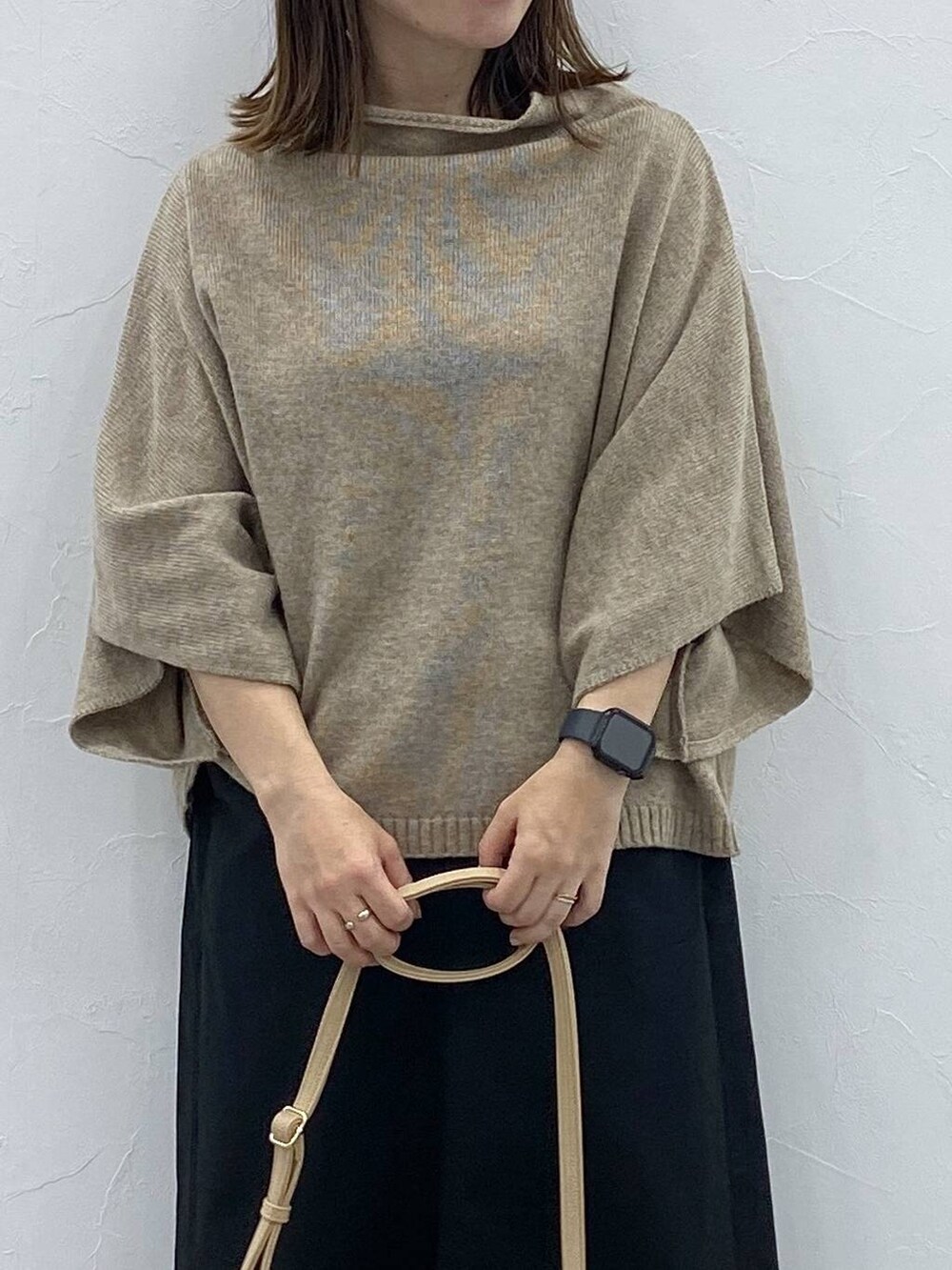 ブラック系のスカート、ベージュ系のベスト、ブラック系のブーツを着用したレディースの秋コーディネートの4枚目の写真