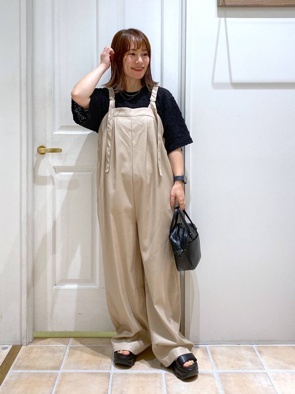 ブラック系のショルダーバッグ、ブラック系のサンダル、ブラック系のTシャツ/カットソーを着用したレディースの秋コーディネートの2枚目の写真