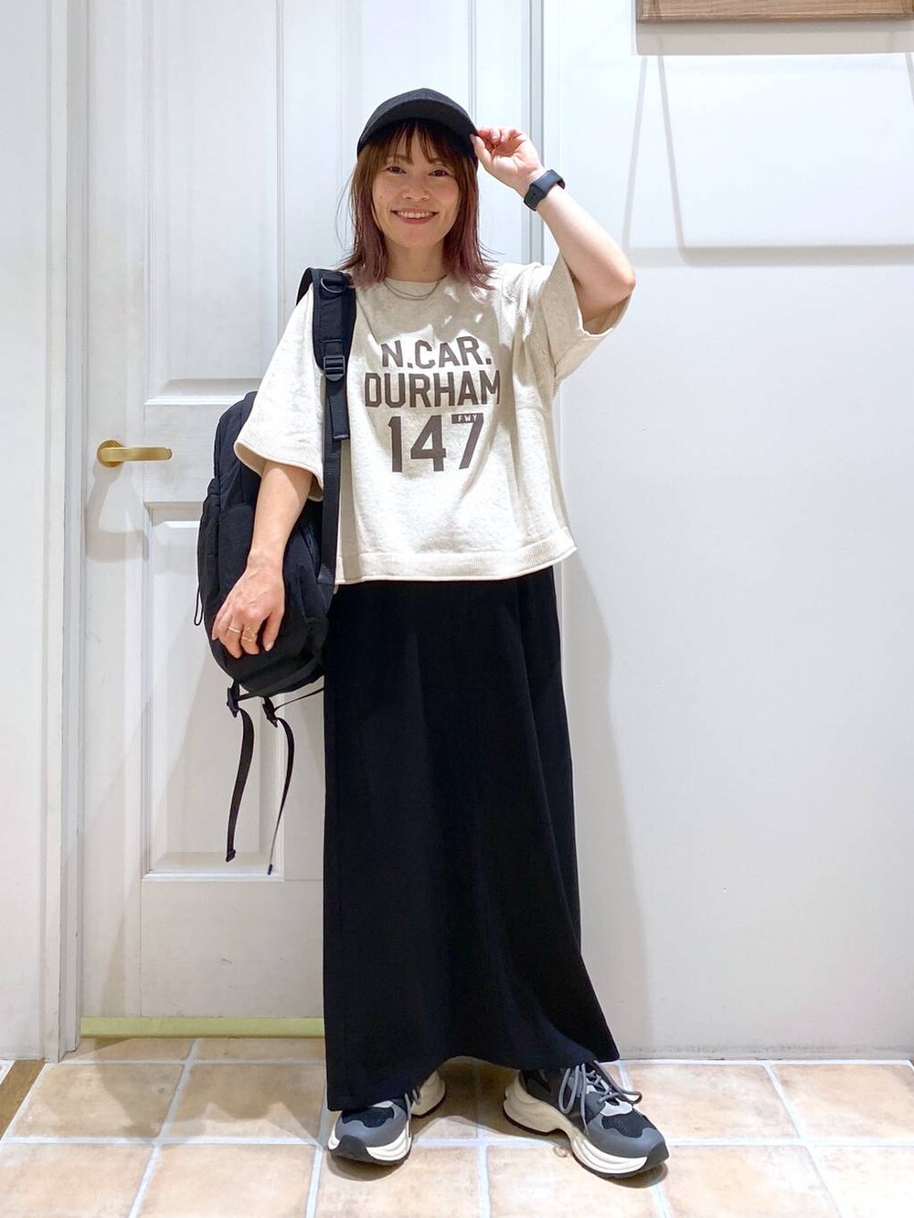 ブラック系のスカート、ブラック系のスニーカー、ベージュ系のTシャツ/カットソーを着用したレディースの秋コーディネートの2枚目の写真