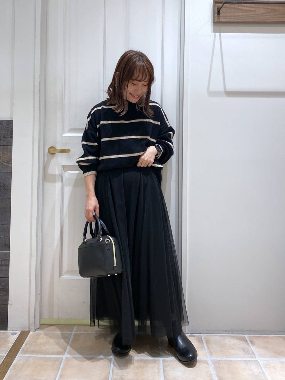 ブラック系のブーツ、その他のニット/セーター、ブラック系のスカートを着用したレディースの冬コーディネートの4枚目の写真