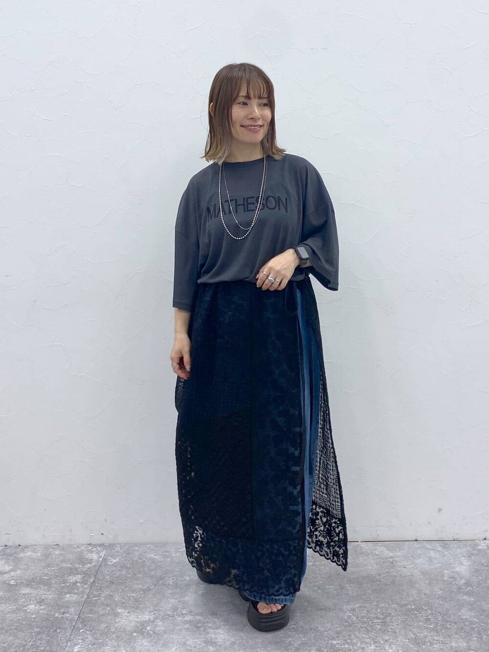 ブラック系のサンダル、ブルー系のデニムパンツ、ブラック系のスカートを着用したレディースの秋コーディネートの2枚目の写真