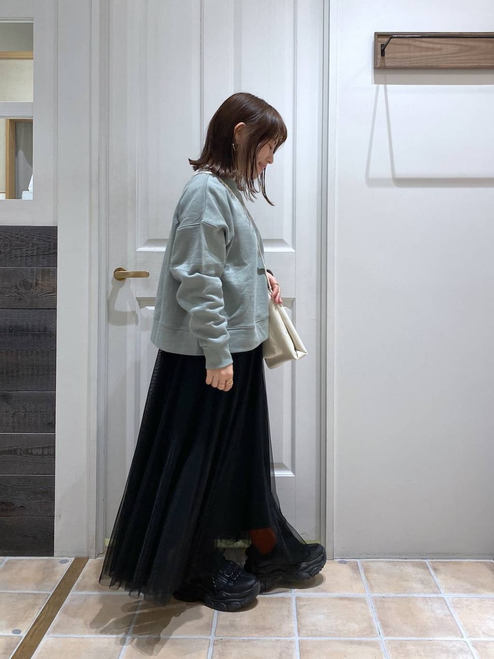 グリーン系のスウェット、ホワイト系のTシャツ/カットソー、ブラック系のスニーカーを着用したレディースの冬コーディネートの5枚目の写真