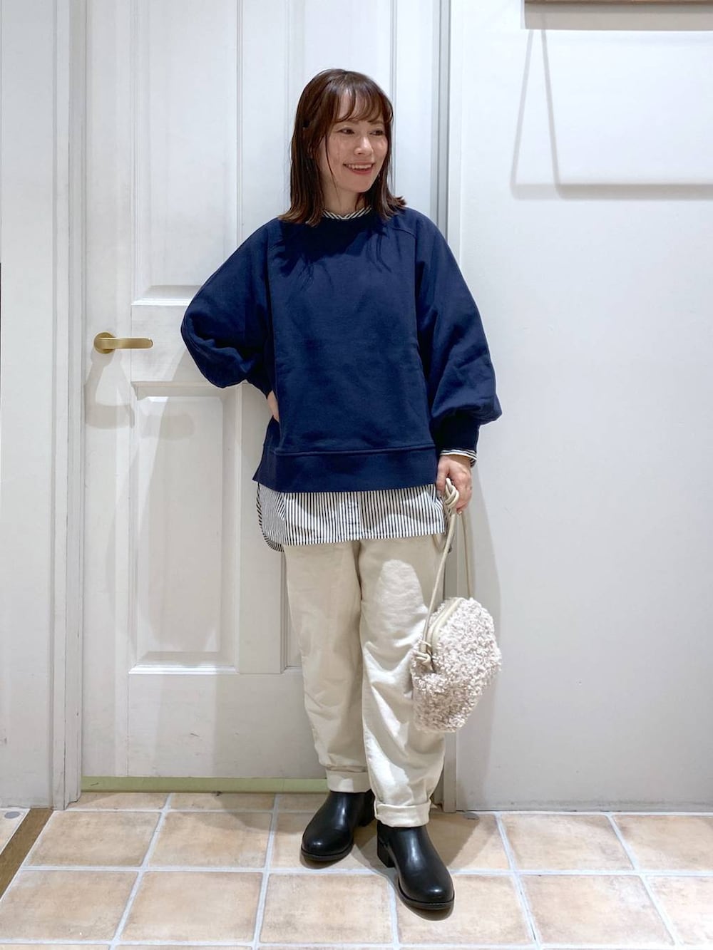 ブルー系のスウェット、ホワイト系のその他パンツ、ブラック系のブーツを着用したレディースの秋コーディネートの2枚目の写真