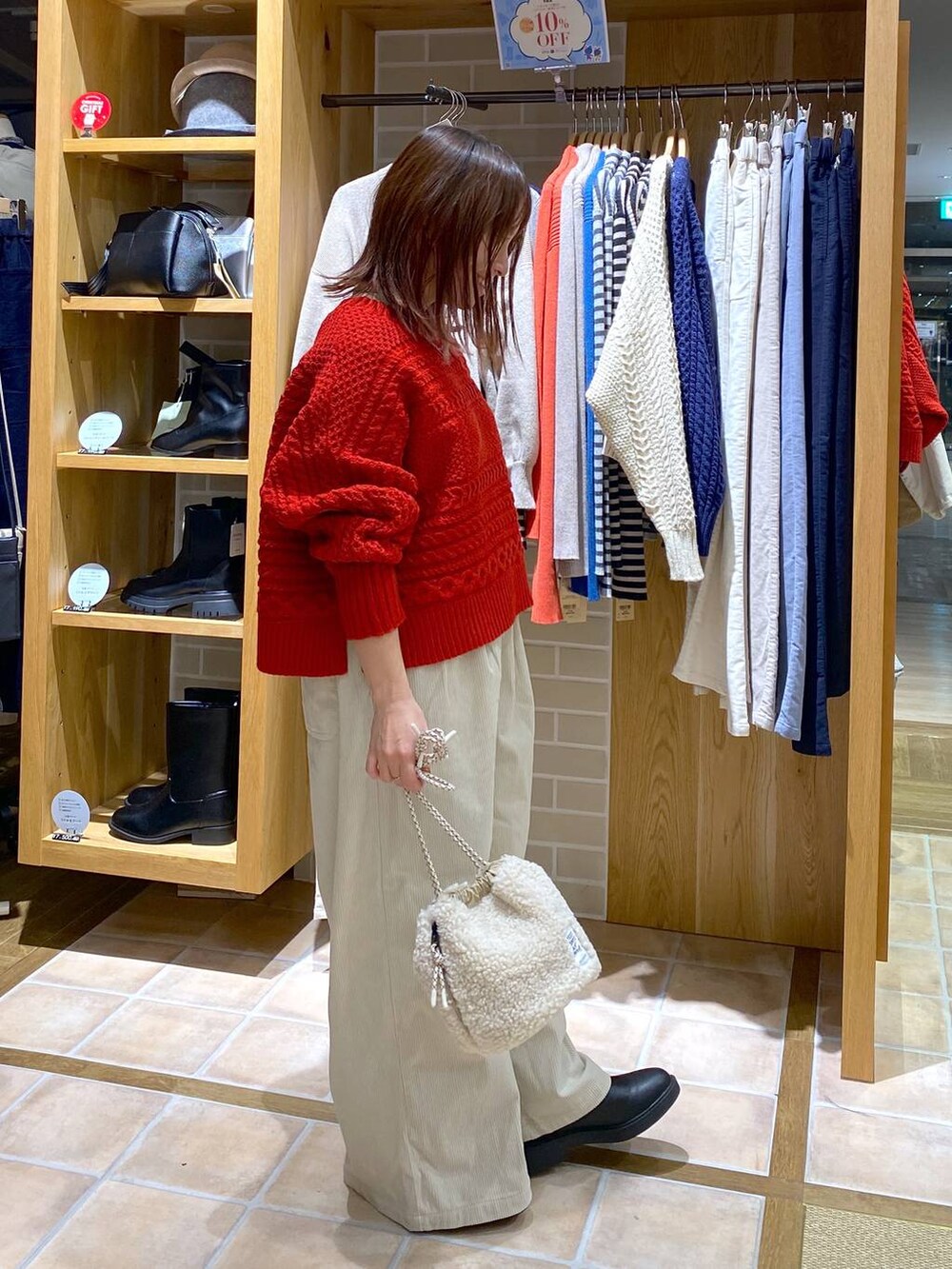 ブラック系のブーツ、ベージュ系のハンドバッグ、シルバー系のネックレスを着用したレディースの秋コーディネートの5枚目の写真