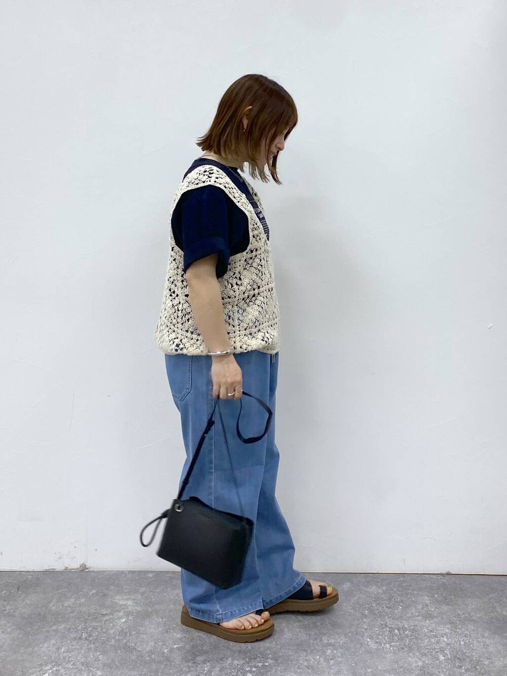 ブラック系のサンダル、ブルー系のデニムパンツ、ブラック系のショルダーバッグを着用したレディースの春コーディネートの4枚目の写真