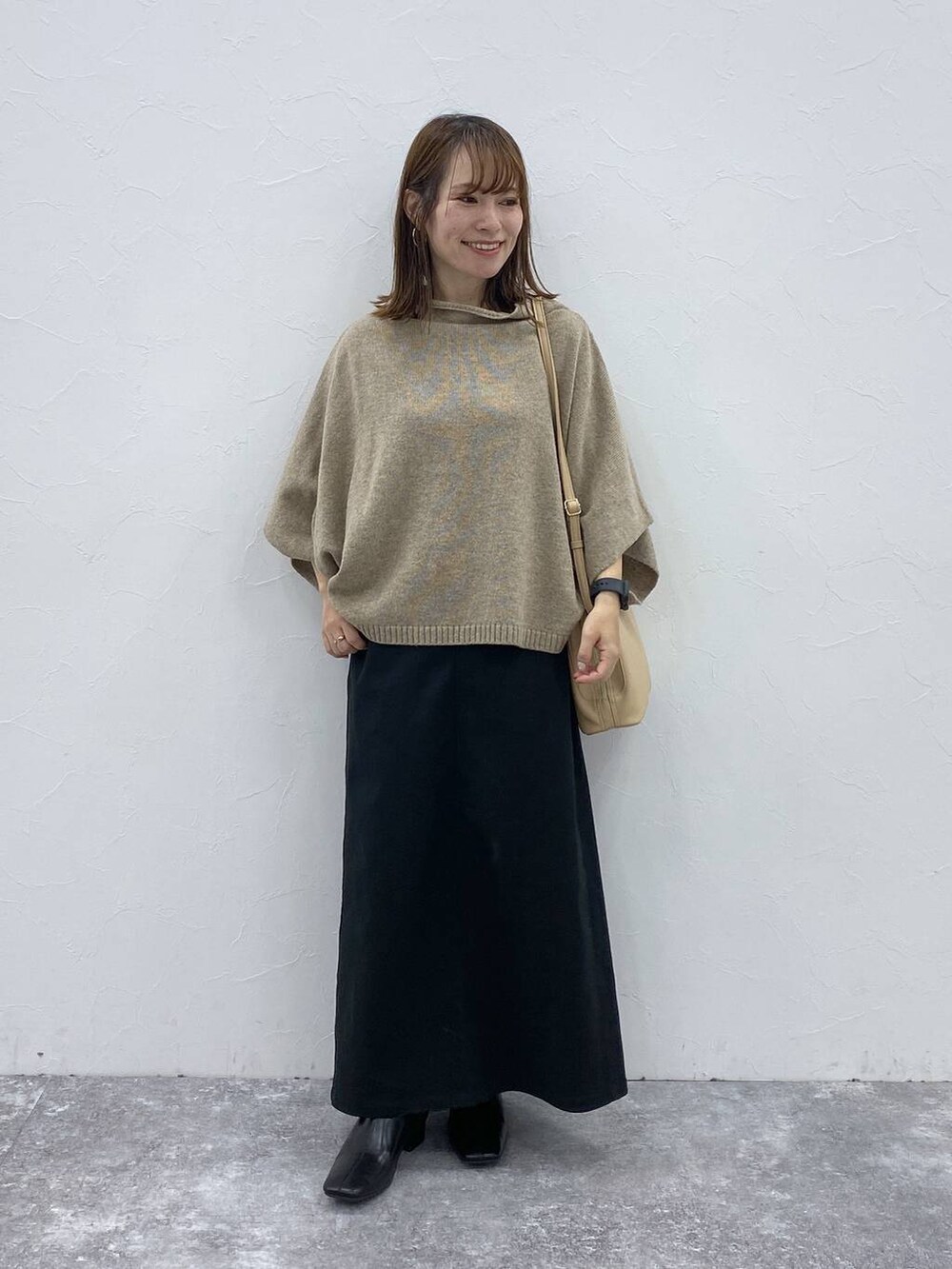 ブラック系のスカート、ベージュ系のベスト、ブラック系のブーツを着用したレディースの秋コーディネートの3枚目の写真