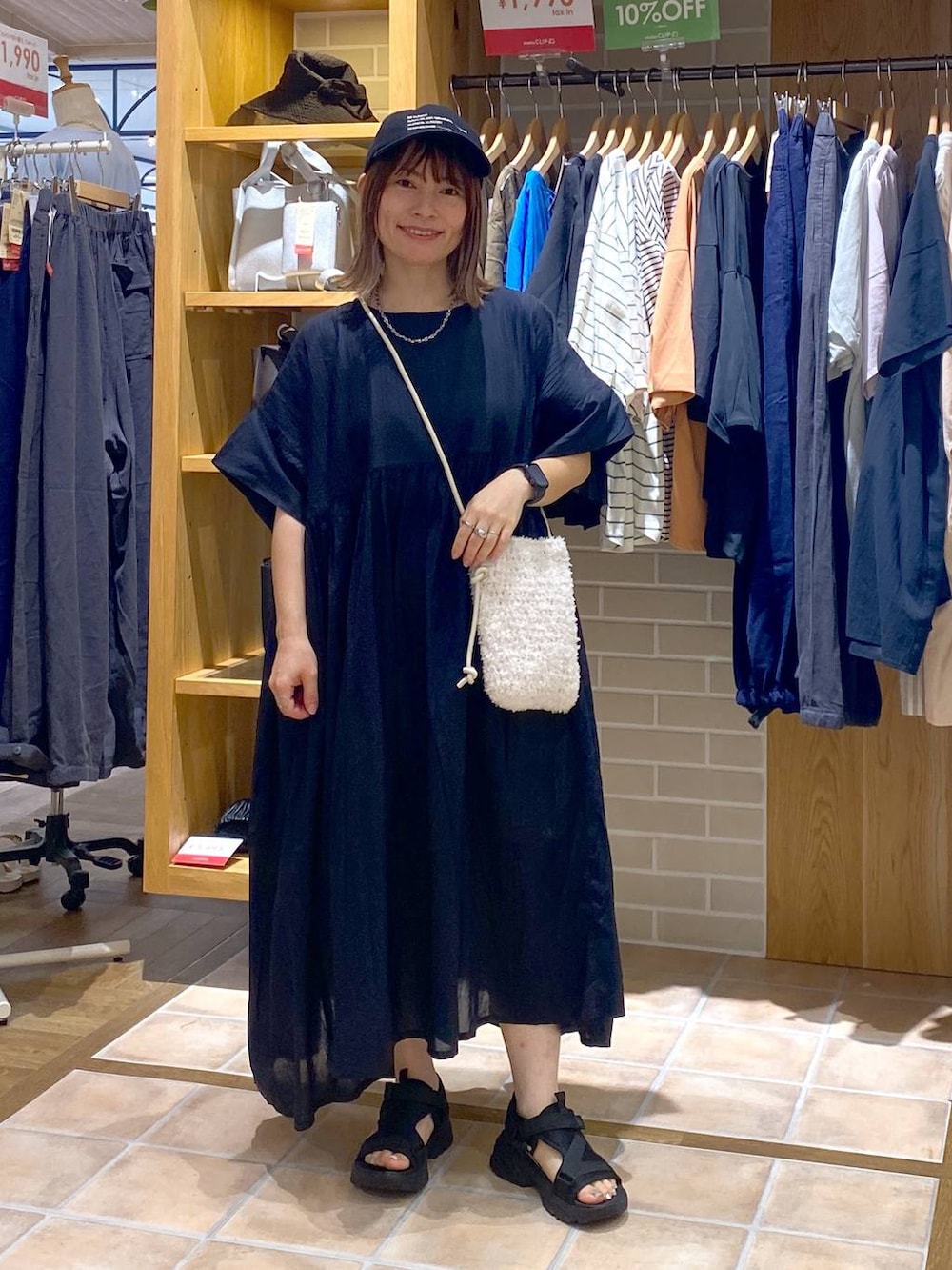 ホワイト系のショルダーバッグ、ブラック系のワンピース、ブラック系のサンダルを着用したレディースの夏コーディネートの2枚目の写真