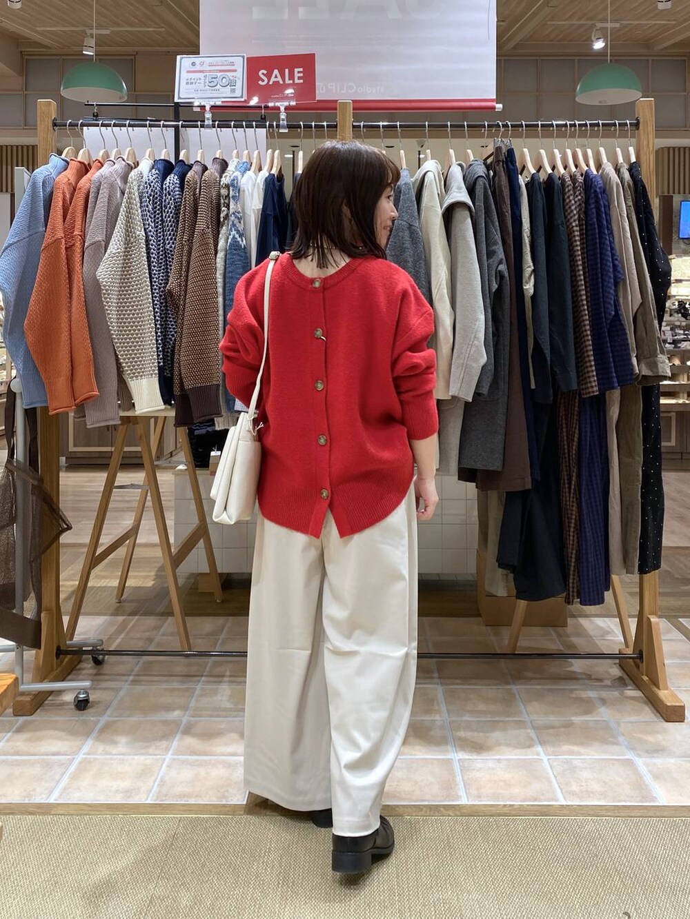 ブラック系のブーツ、ベージュ系のその他パンツ、レッド系のカーディガン/ボレロを着用したレディースの冬コーディネートの7枚目の写真