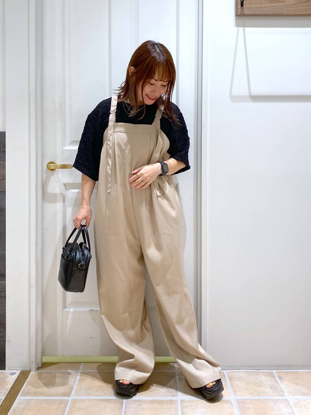 ブラック系のショルダーバッグ、ブラック系のサンダル、ブラック系のTシャツ/カットソーを着用したレディースの秋コーディネートの4枚目の写真