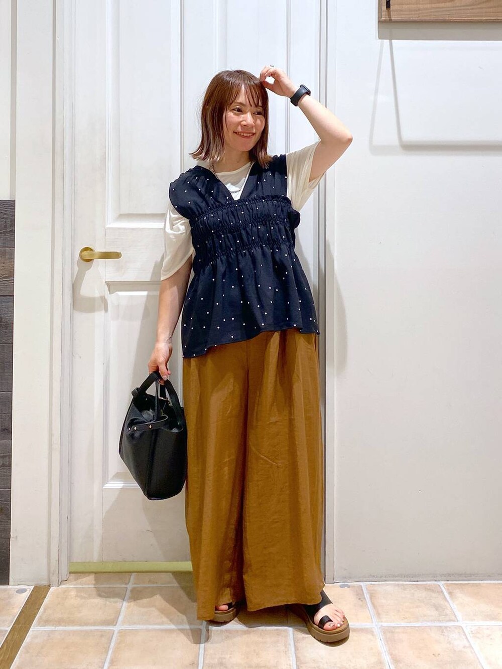 ブラック系のサンダル、ホワイト系のTシャツ/カットソー、ブラック系のショルダーバッグを着用したレディースの夏コーディネートの2枚目の写真