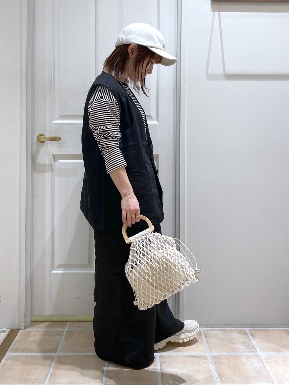 ベージュ系のスニーカー、ブラック系のその他パンツ、ブラック系のベストを着用したレディースの春コーディネートの5枚目の写真