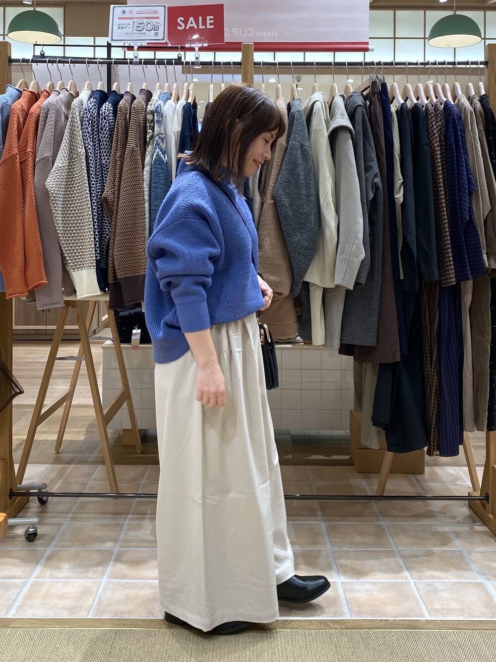 ブラック系のブーツ、ブルー系のニット/セーター、ベージュ系のその他パンツを着用したレディースの冬コーディネートの5枚目の写真