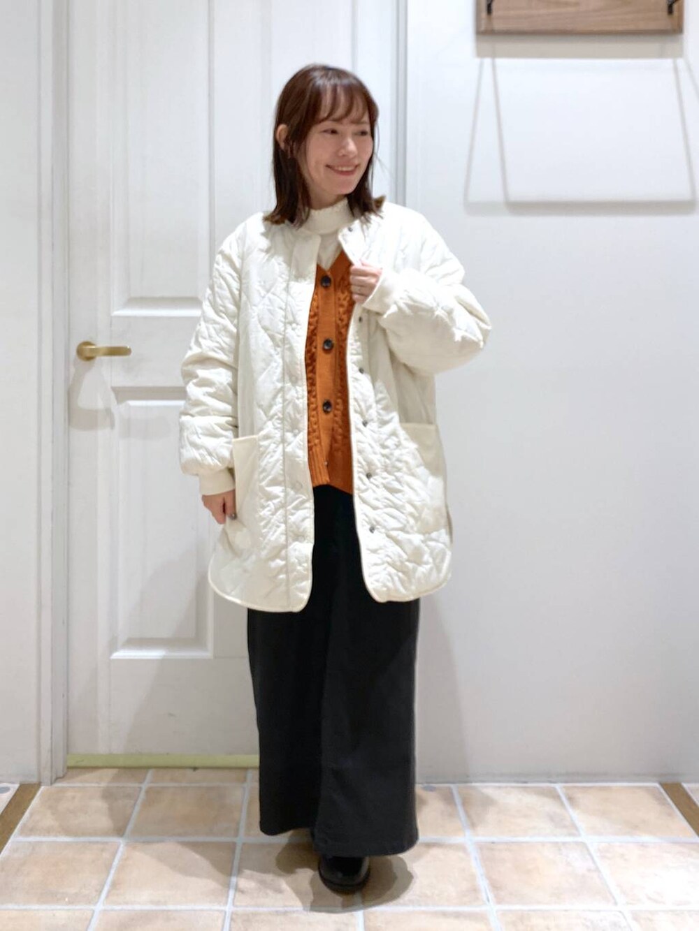 ブラック系のスカート、ホワイト系のTシャツ/カットソー、ホワイト系のノーカラーコートを着用したレディースの秋コーディネートの3枚目の写真