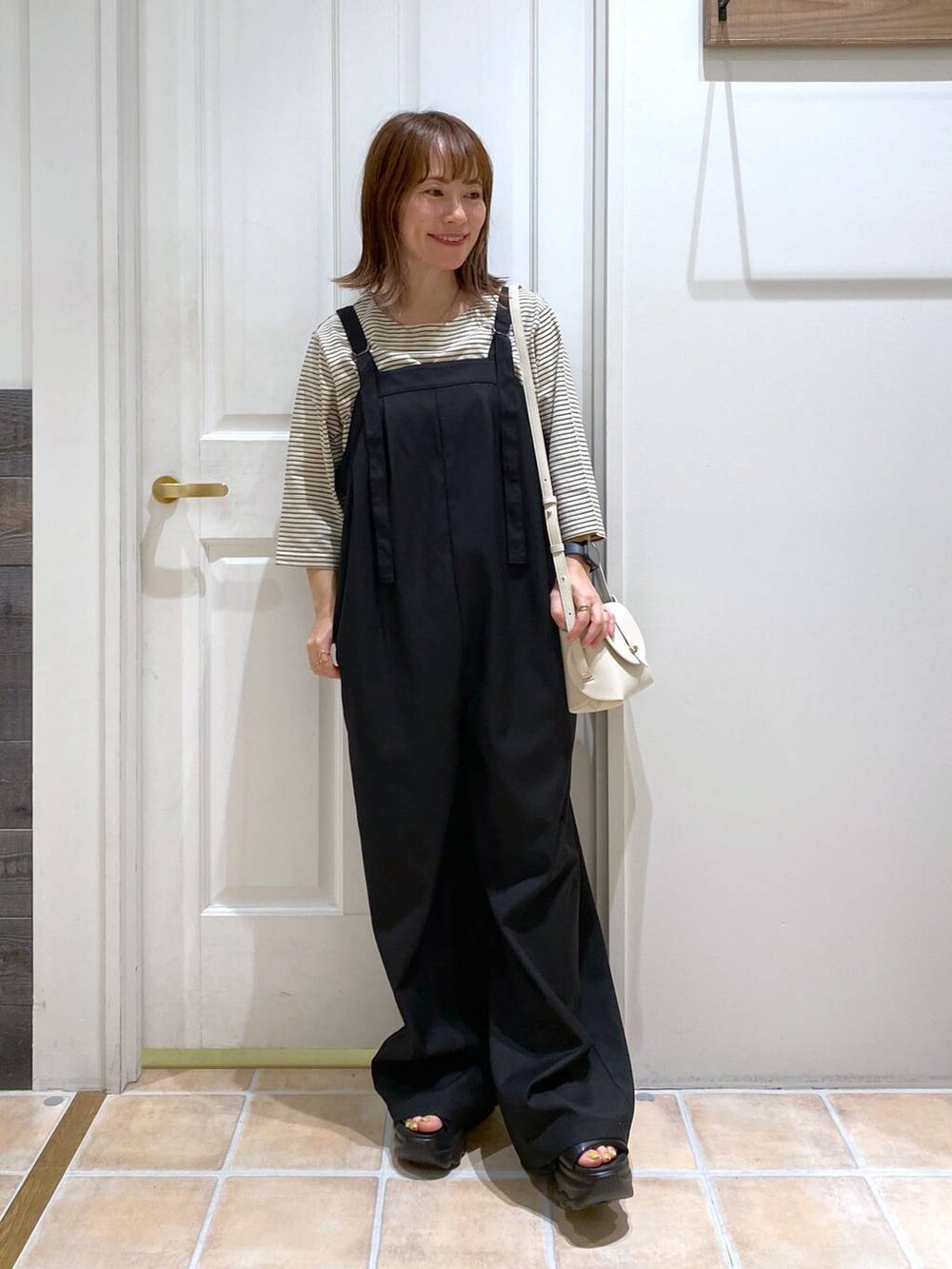 ブラック系のサンダル、ホワイト系のショルダーバッグ、シルバー系のネックレスを着用したレディースの夏コーディネートの4枚目の写真