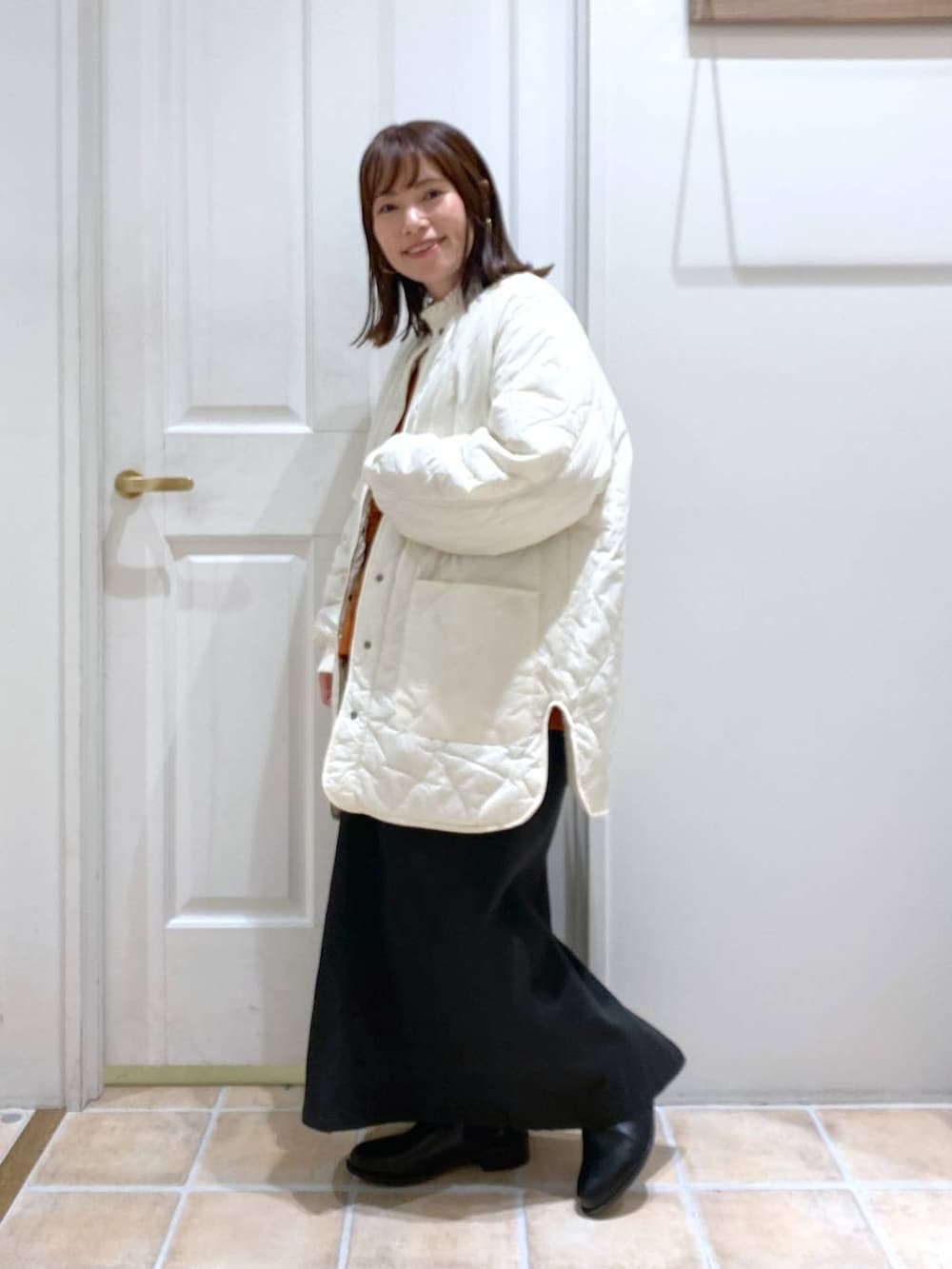 ブラック系のスカート、ホワイト系のTシャツ/カットソー、ホワイト系のノーカラーコートを着用したレディースの秋コーディネートの2枚目の写真