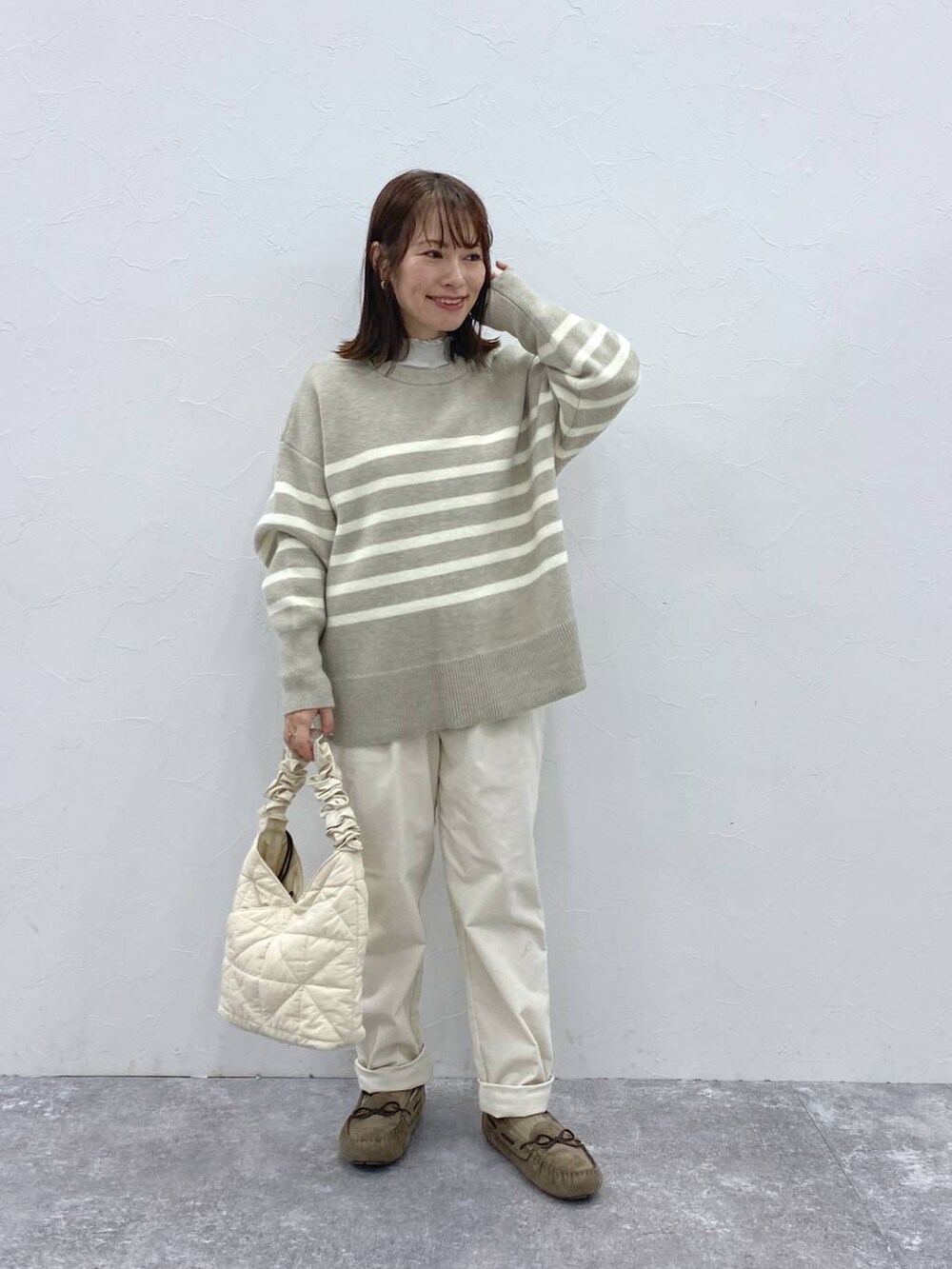 グレー系のTシャツ/カットソー、グレー系のモカシン/デッキシューズ、ベージュ系のトートバッグを着用したレディースの冬コーディネートの3枚目の写真