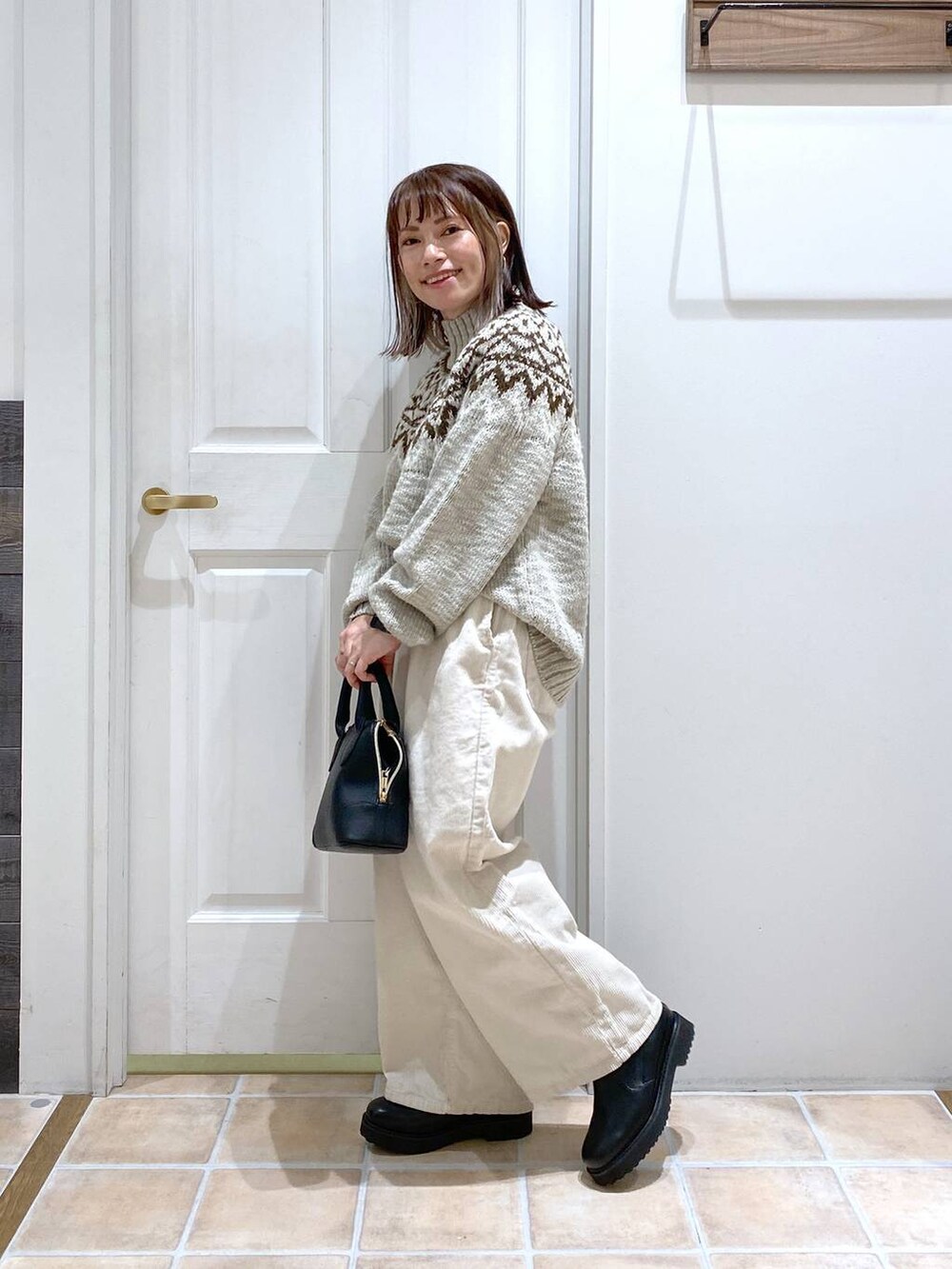 ホワイト系のその他パンツ、ブラック系のブーツ、ブラック系のショルダーバッグを着用したレディースの秋コーディネートの4枚目の写真
