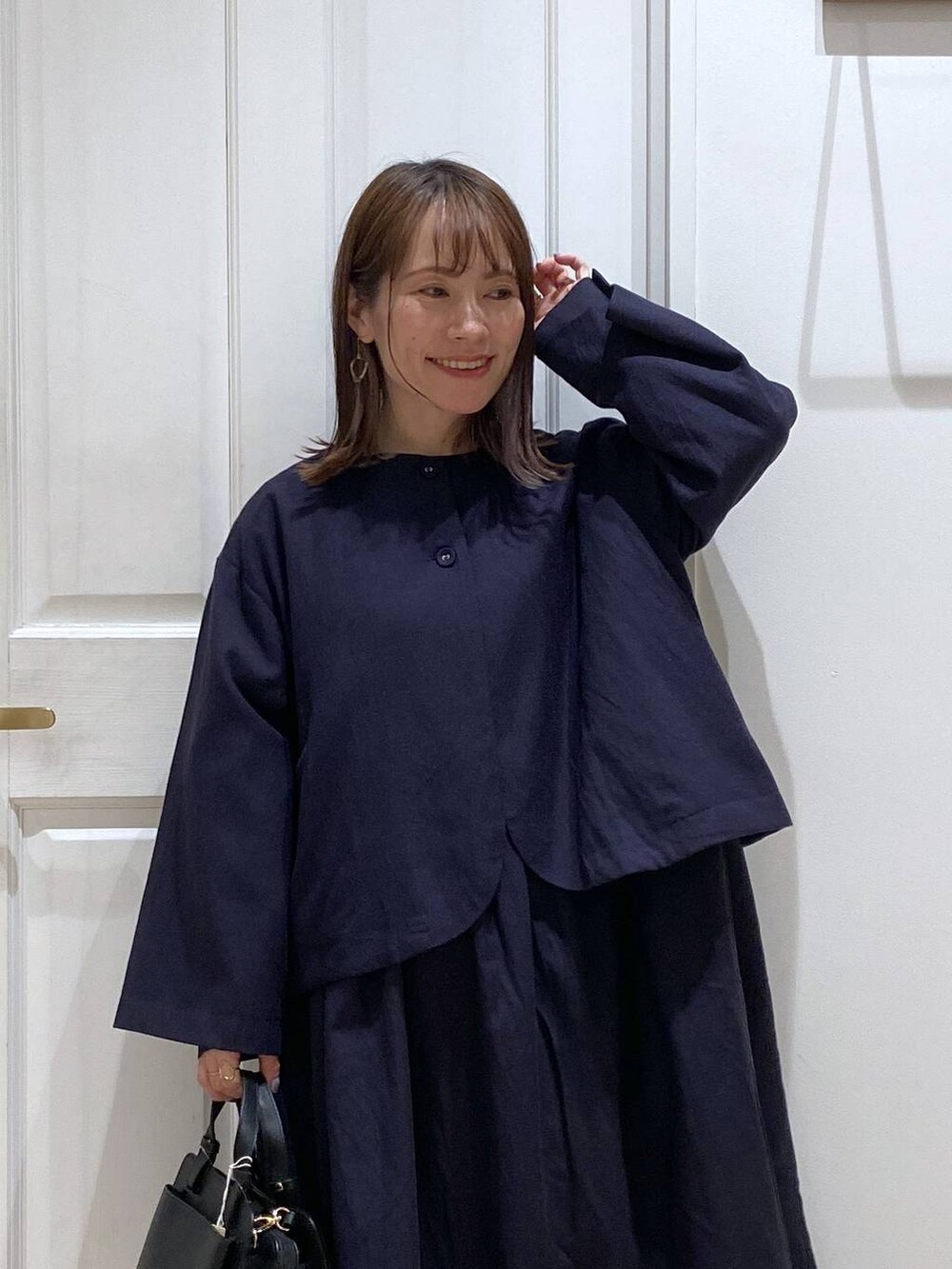 ブラック系のパンプス、ブルー系のセットアップ、その他のピアス（両耳用）を着用したレディースの冬コーディネートの4枚目の写真