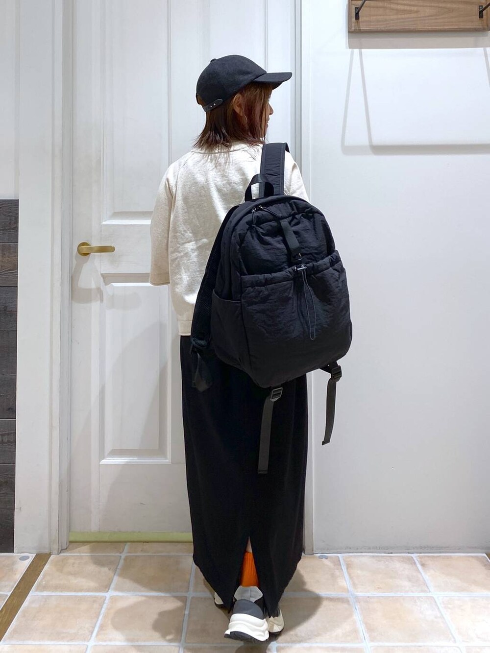 ブラック系のスカート、ブラック系のスニーカー、ベージュ系のTシャツ/カットソーを着用したレディースの秋コーディネートの6枚目の写真