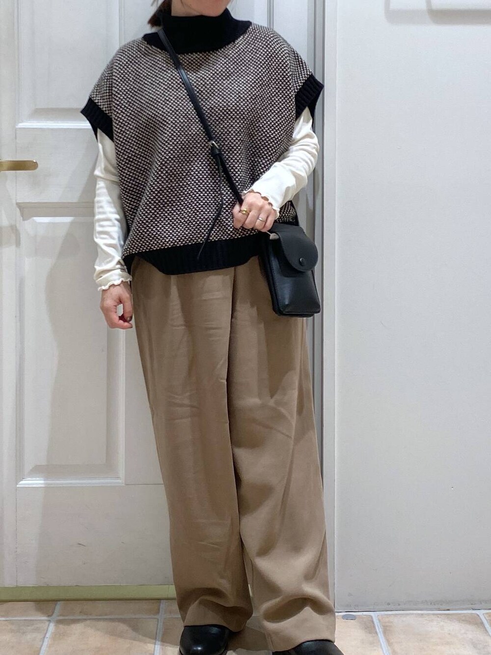 ホワイト系のTシャツ/カットソー、ブラック系のブーツ、ブラック系のベストを着用したレディースの冬コーディネートの4枚目の写真