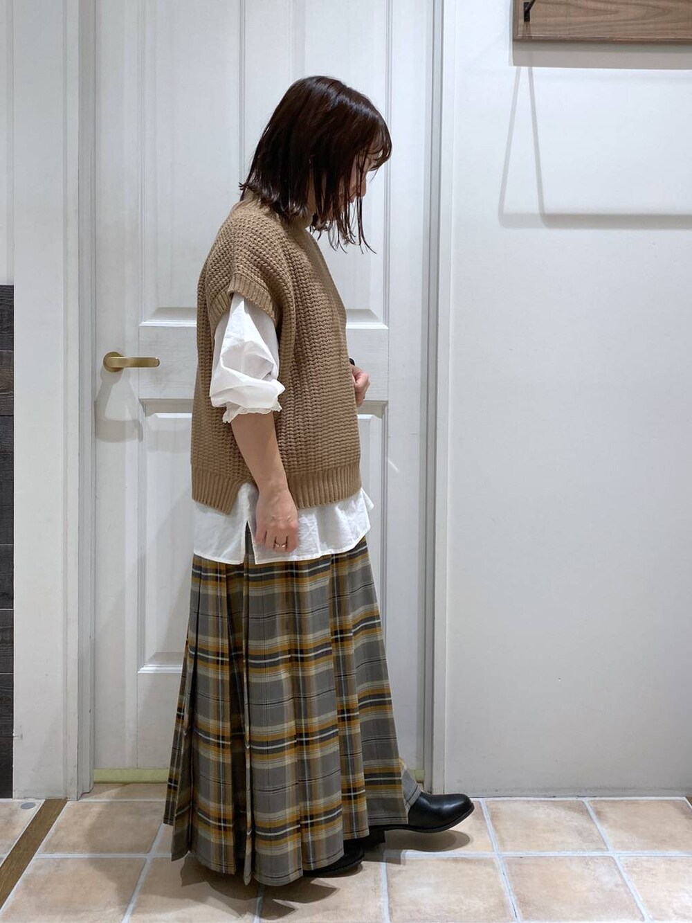 ブラック系のブーツ、ブラウン系のベスト、ホワイト系のシャツ/ブラウスを着用したレディースの秋コーディネートの5枚目の写真