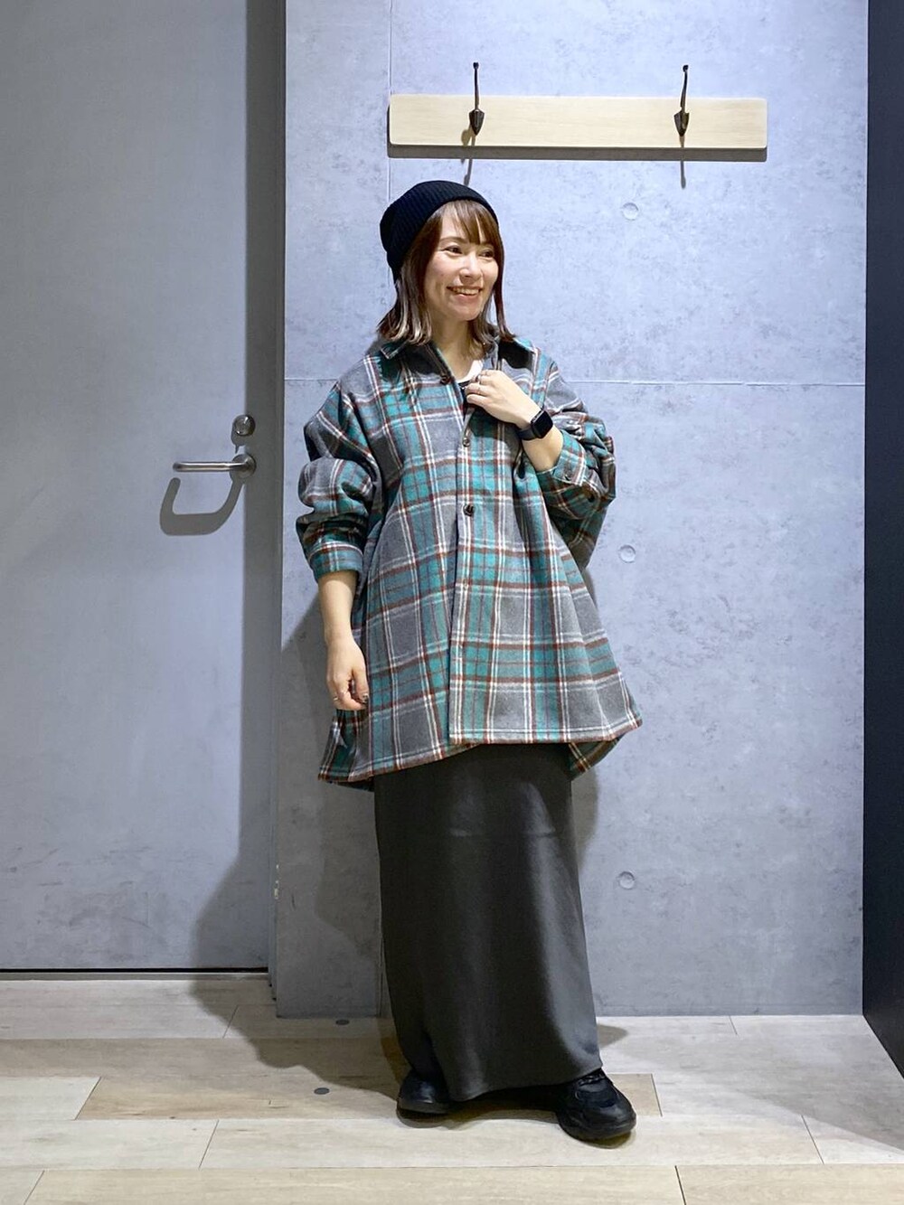 グレー系のスカート、ブラック系のスニーカー、グレー系のシャツ/ブラウスを着用したレディースの秋コーディネートの2枚目の写真