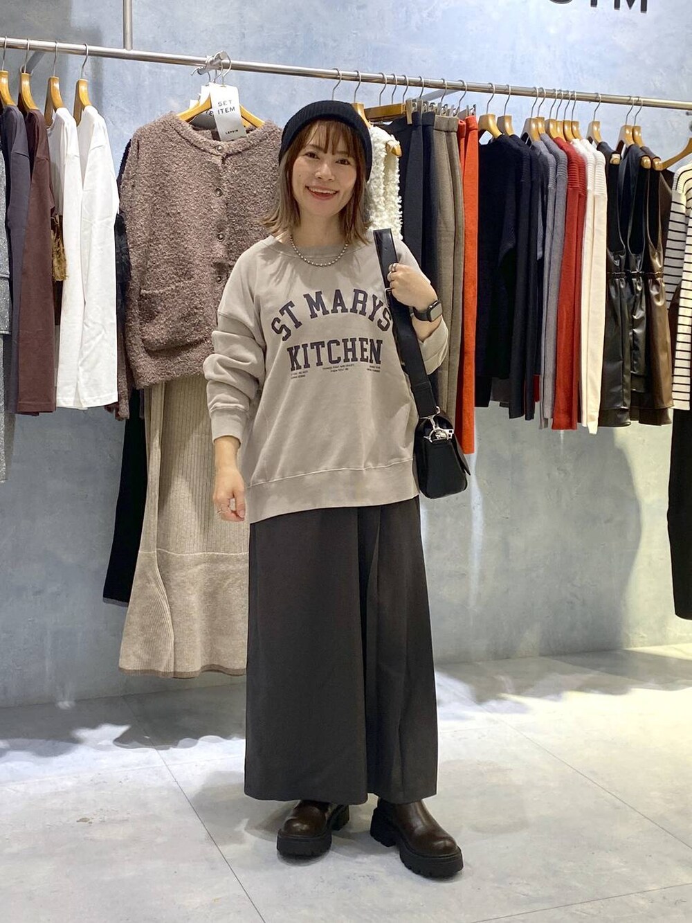 ブラック系のショルダーバッグ、ブラック系のブーツ、グレー系のスカートを着用したレディースの秋コーディネートの2枚目の写真