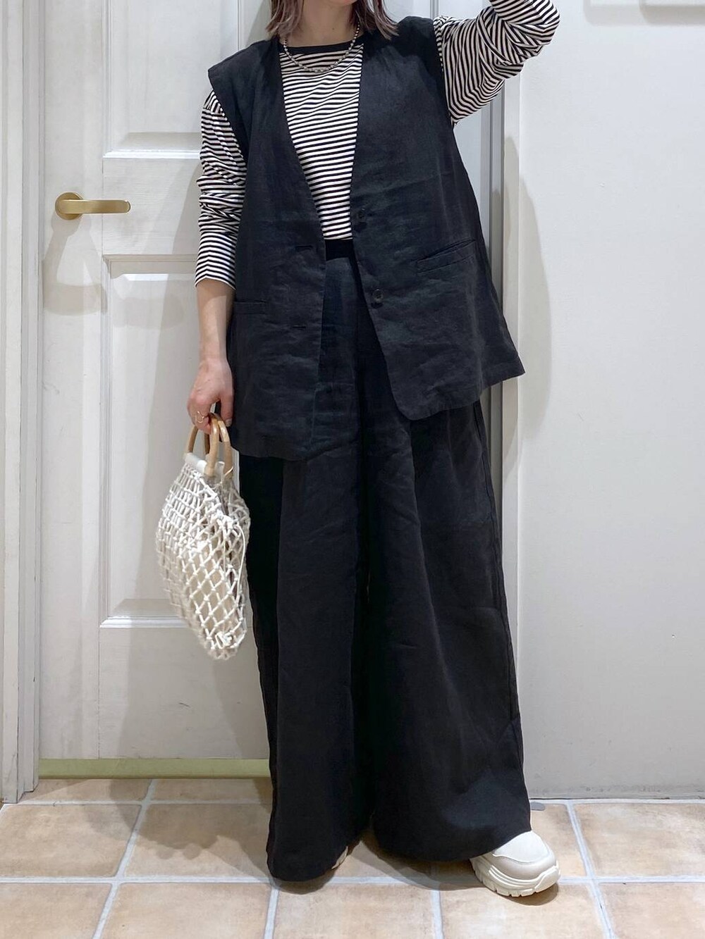 ベージュ系のスニーカー、ブラック系のその他パンツ、ブラック系のベストを着用したレディースの春コーディネートの3枚目の写真