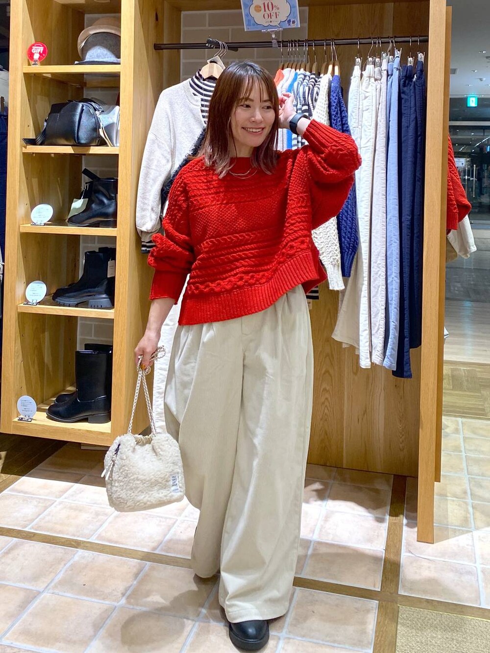 ブラック系のブーツ、ベージュ系のハンドバッグ、シルバー系のネックレスを着用したレディースの秋コーディネートの3枚目の写真