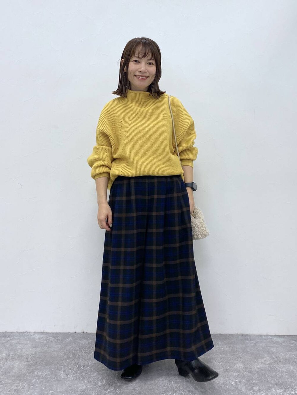 ブラック系のブーツ、イエロー系のニット/セーター、ベージュ系のトートバッグを着用したレディースの秋コーディネートの2枚目の写真