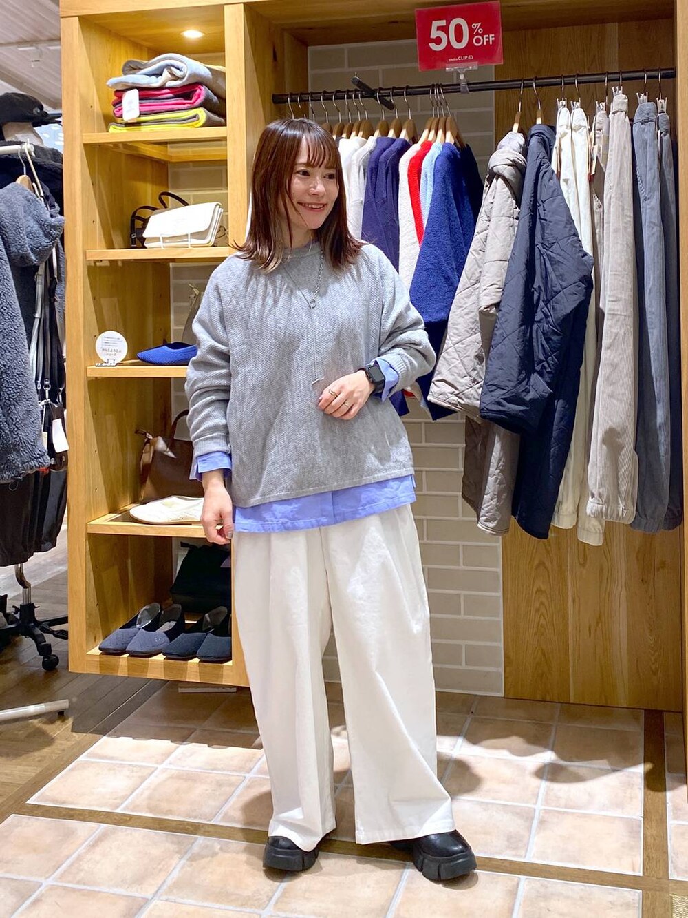 ブルー系のシャツ/ブラウス、ブラック系のブーツ、グレー系のニット/セーターを着用したレディースの冬コーディネートの2枚目の写真