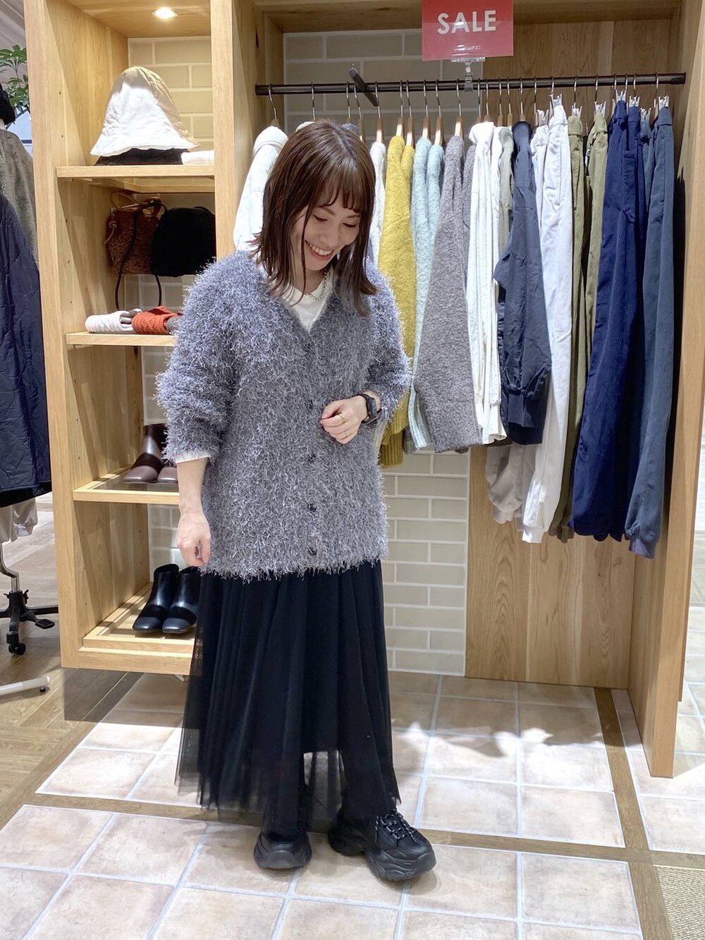 ブラック系のスニーカー、ブラック系のスカート、グレー系のカーディガン/ボレロを着用したレディースの冬コーディネートの2枚目の写真