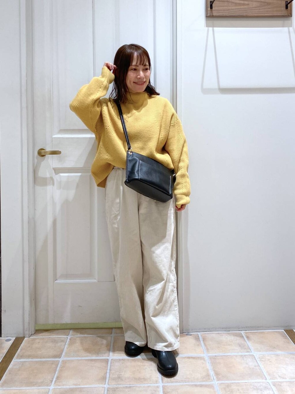 ホワイト系のその他パンツ、ブラック系のブーツ、イエロー系のニット/セーターを着用したレディースの冬コーディネートの2枚目の写真