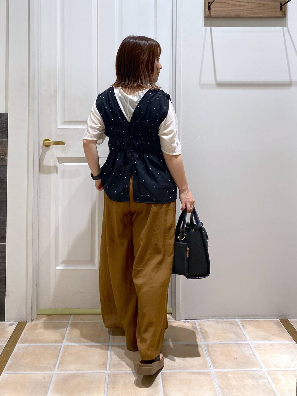 ブラック系のサンダル、ホワイト系のTシャツ/カットソー、ブラック系のショルダーバッグを着用したレディースの夏コーディネートの5枚目の写真