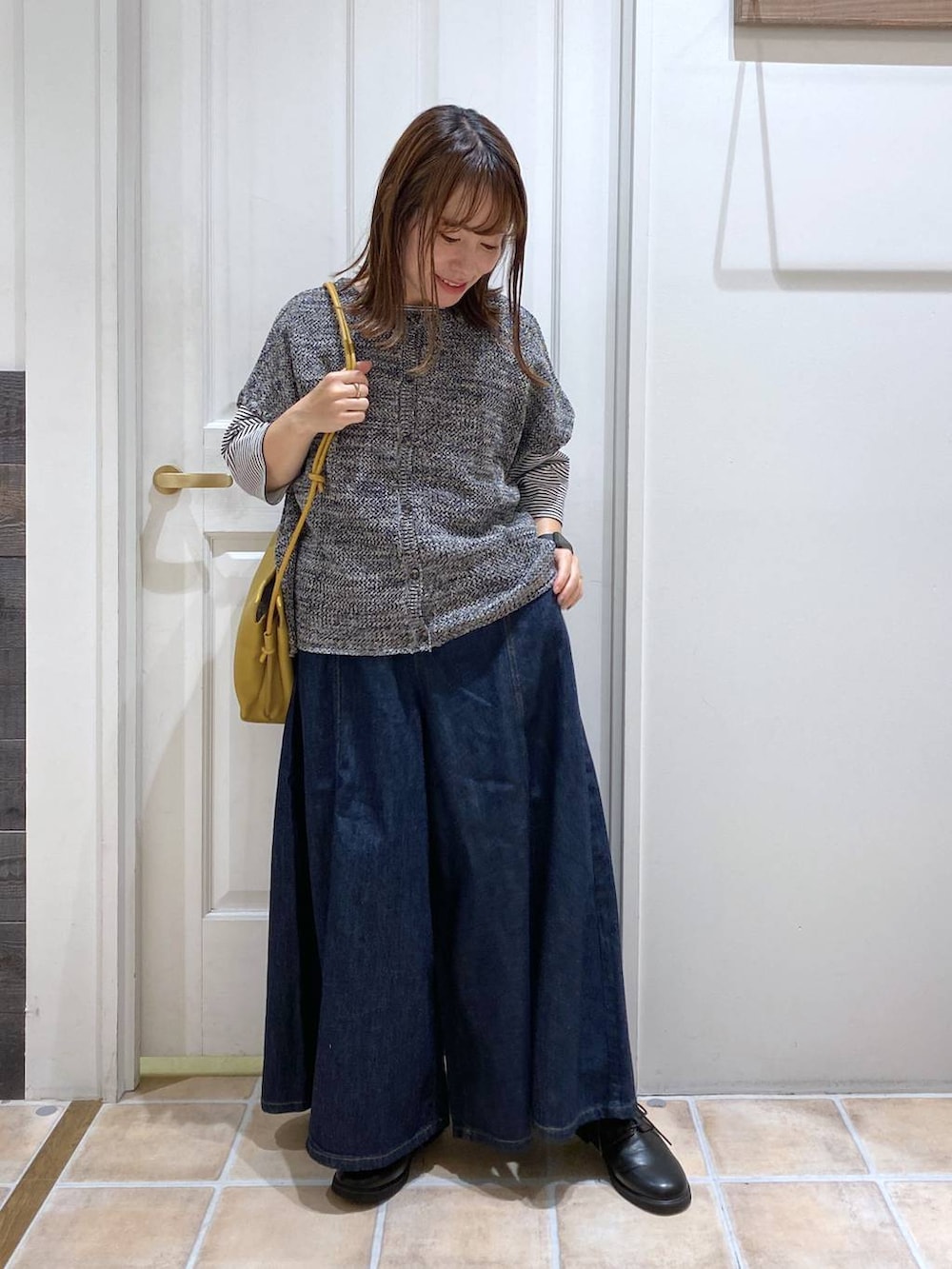 ブルー系のデニムパンツ、ブラック系のドレスシューズ、イエロー系のショルダーバッグを着用したレディースの夏コーディネートの2枚目の写真