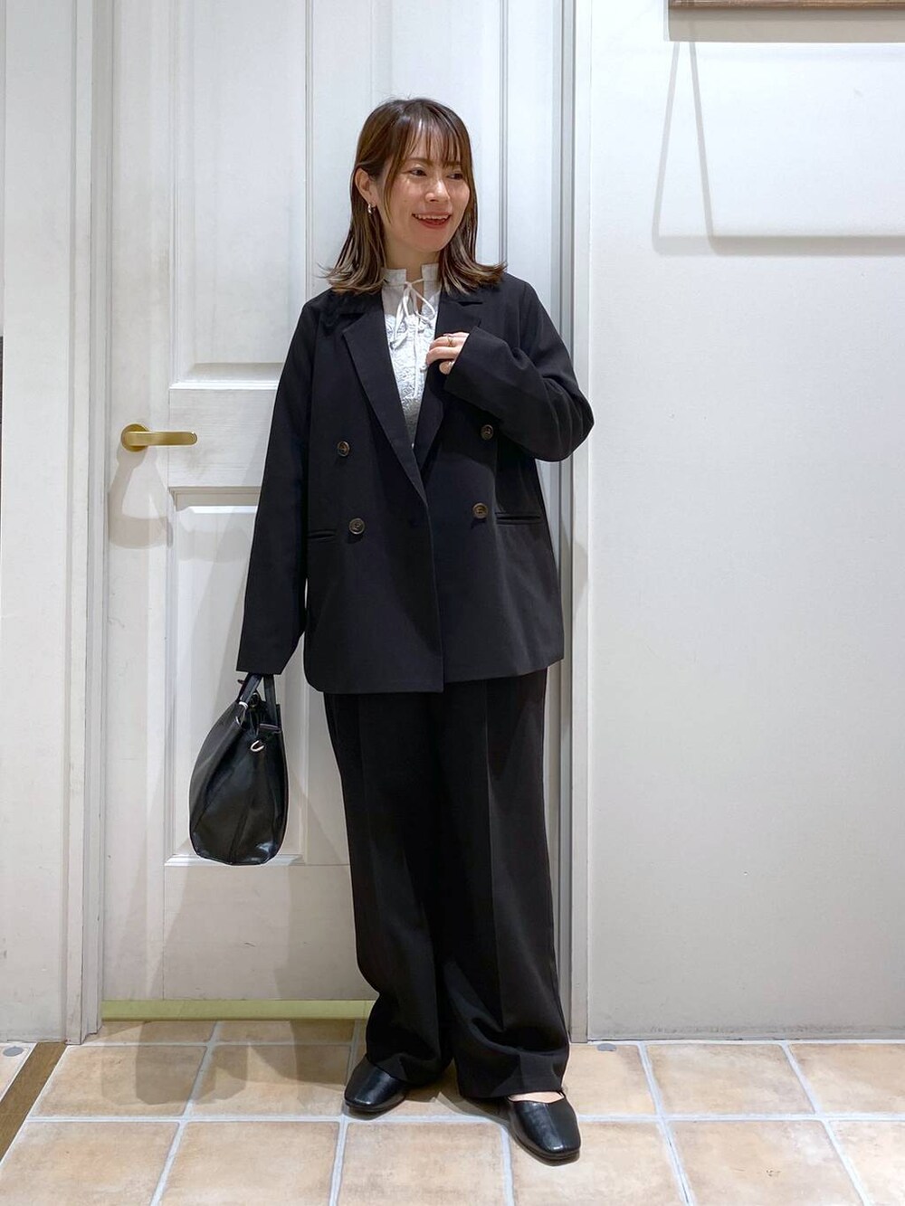 ブラック系のパンプス、ブラック系のスラックス、ブラック系のショルダーバッグを着用したレディースの冬コーディネートの3枚目の写真