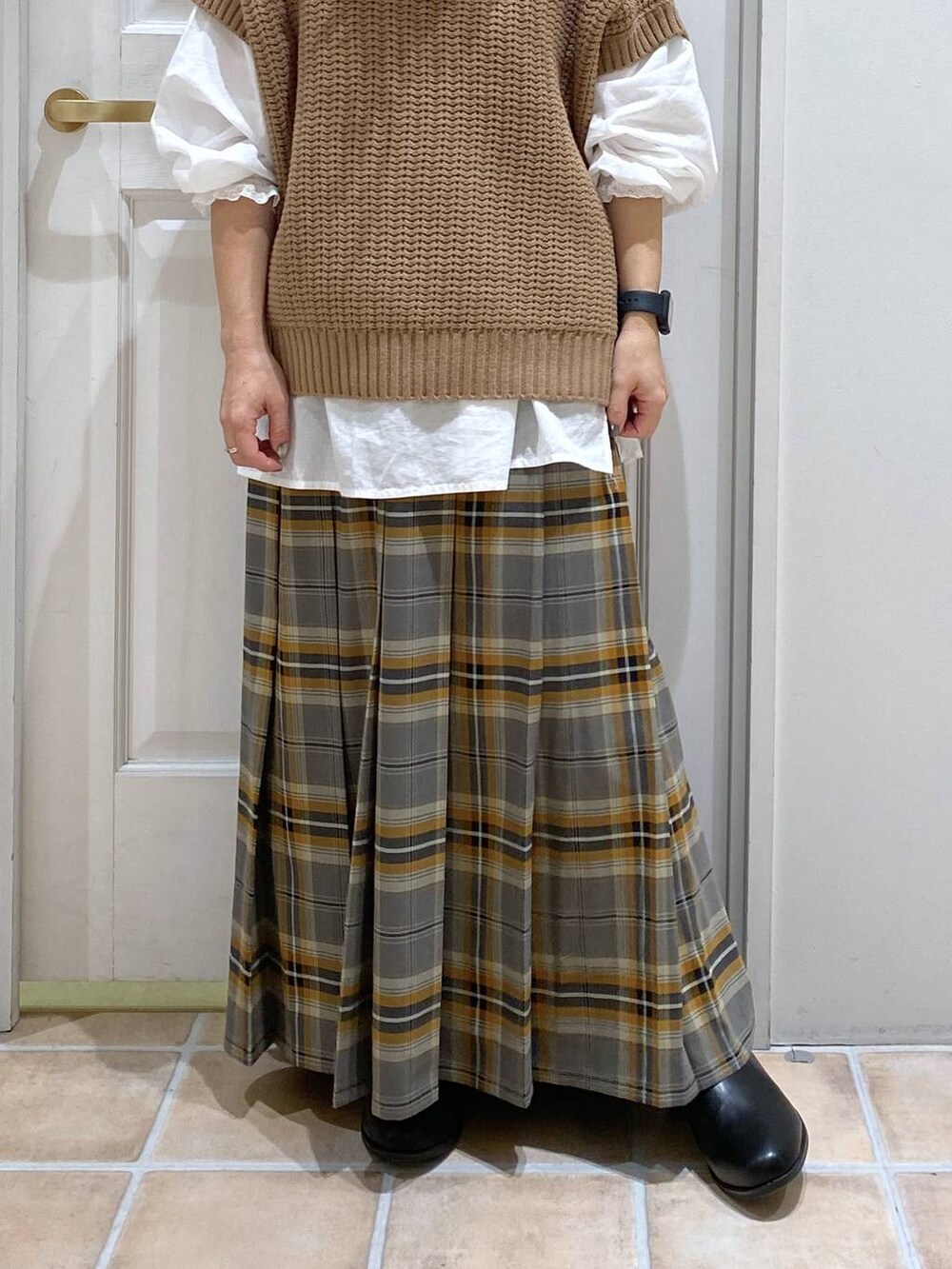 ブラック系のブーツ、ブラウン系のベスト、ホワイト系のシャツ/ブラウスを着用したレディースの秋コーディネートの3枚目の写真