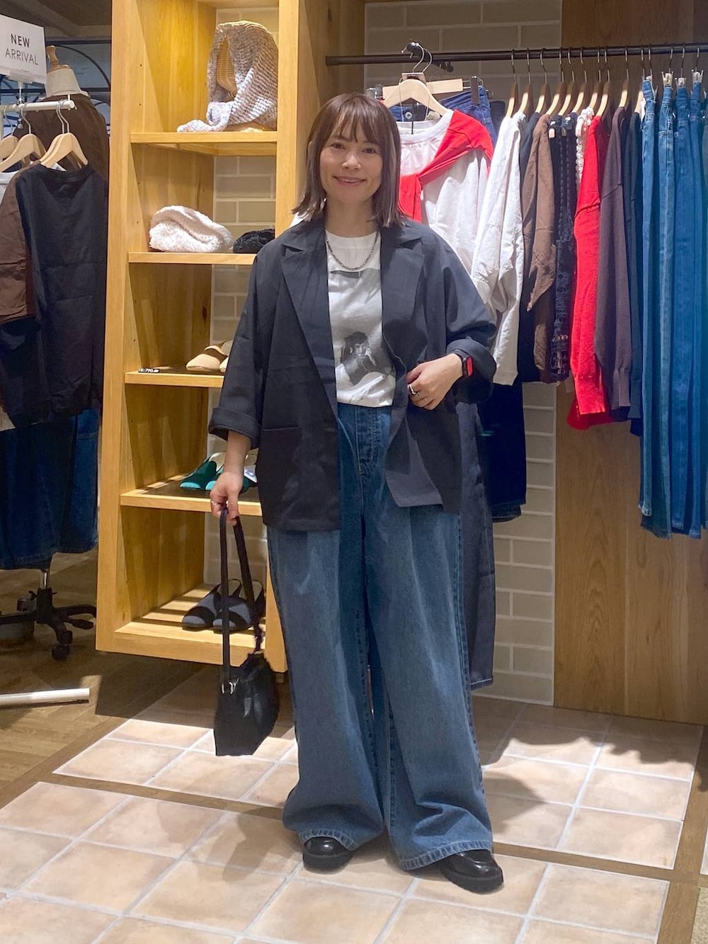 ブルー系のデニムパンツ、ブラック系のローファー、ブラック系のショルダーバッグを着用したレディースの秋コーディネートの2枚目の写真